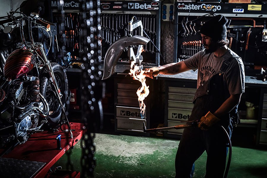 Trabajador de la empresa Inspiración Metálica Motor Company manipulando una pieza de metal con un soplete